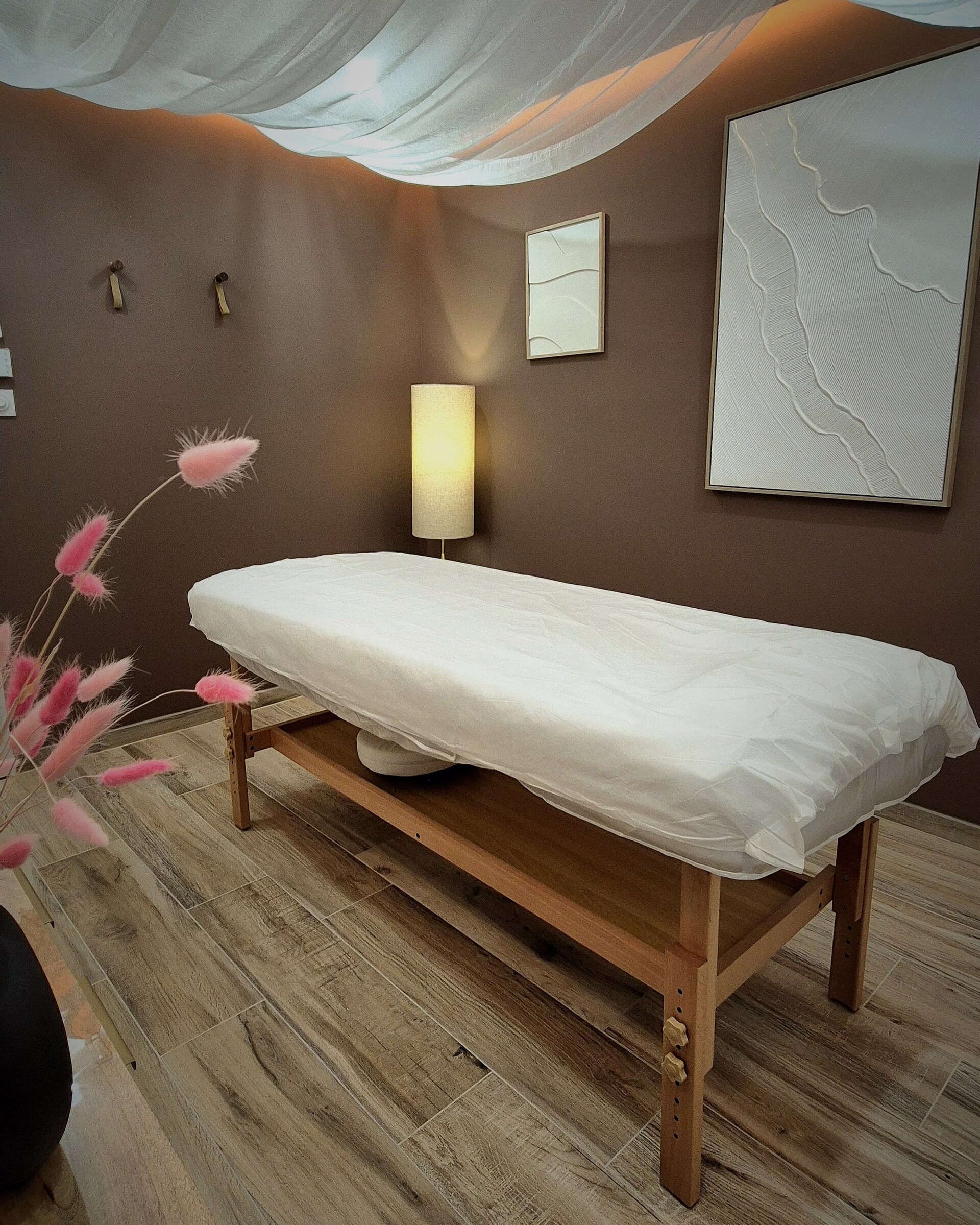 Salle de massage privative avec table, voilages et lampe cocon